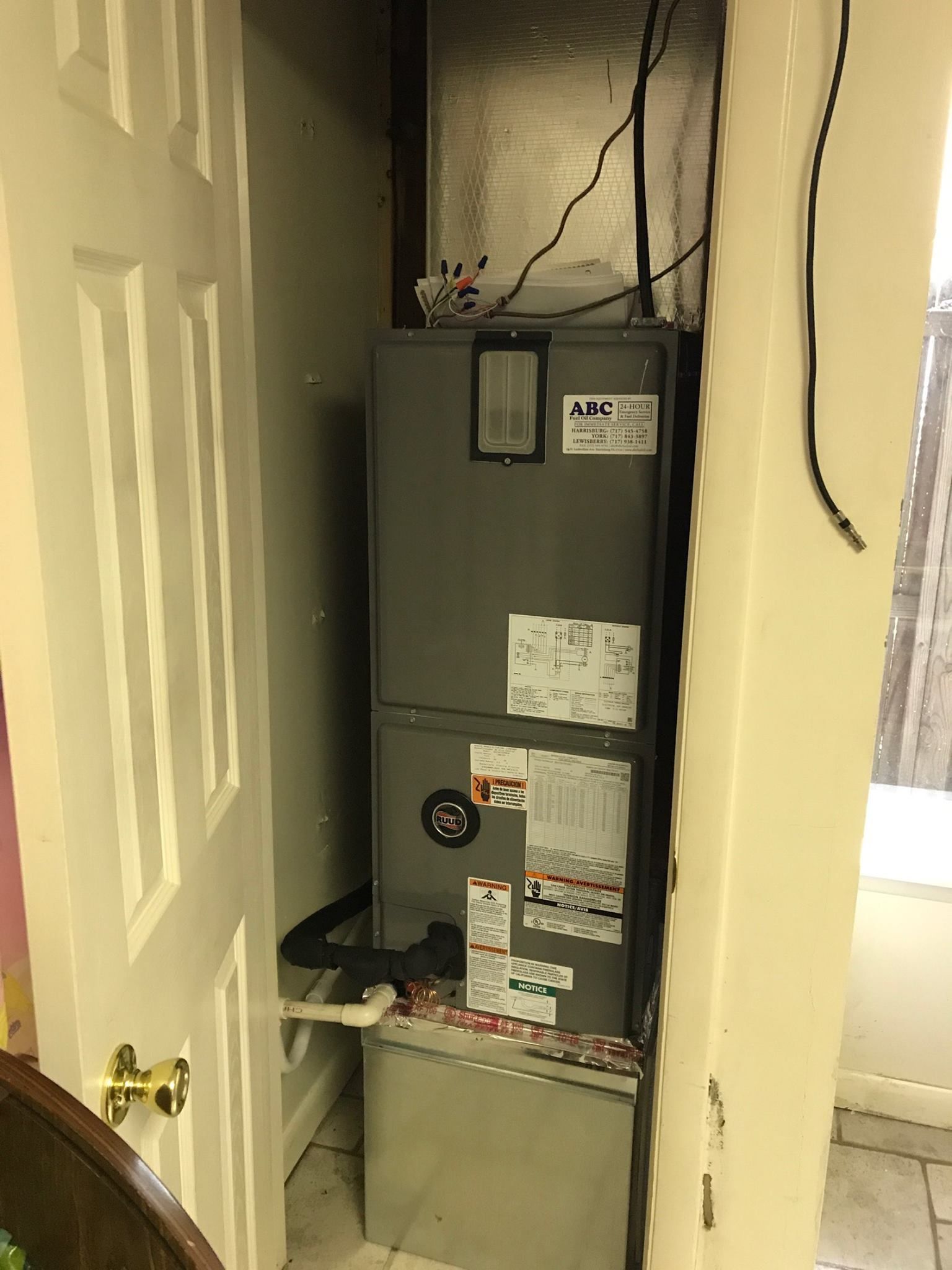 A tall HVAC unit is inside a closet, with a white door to the left.