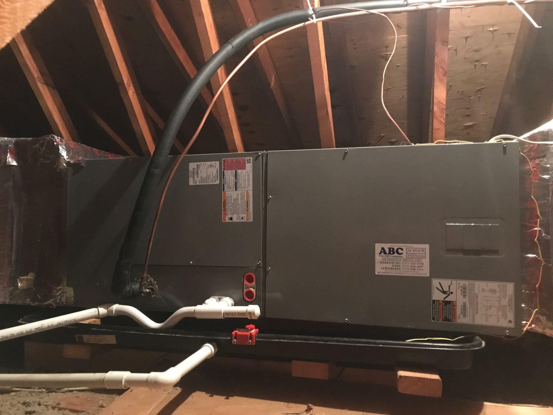 HVAC unit in an attic with ductwork, PVC pipes, and a condensation pan.