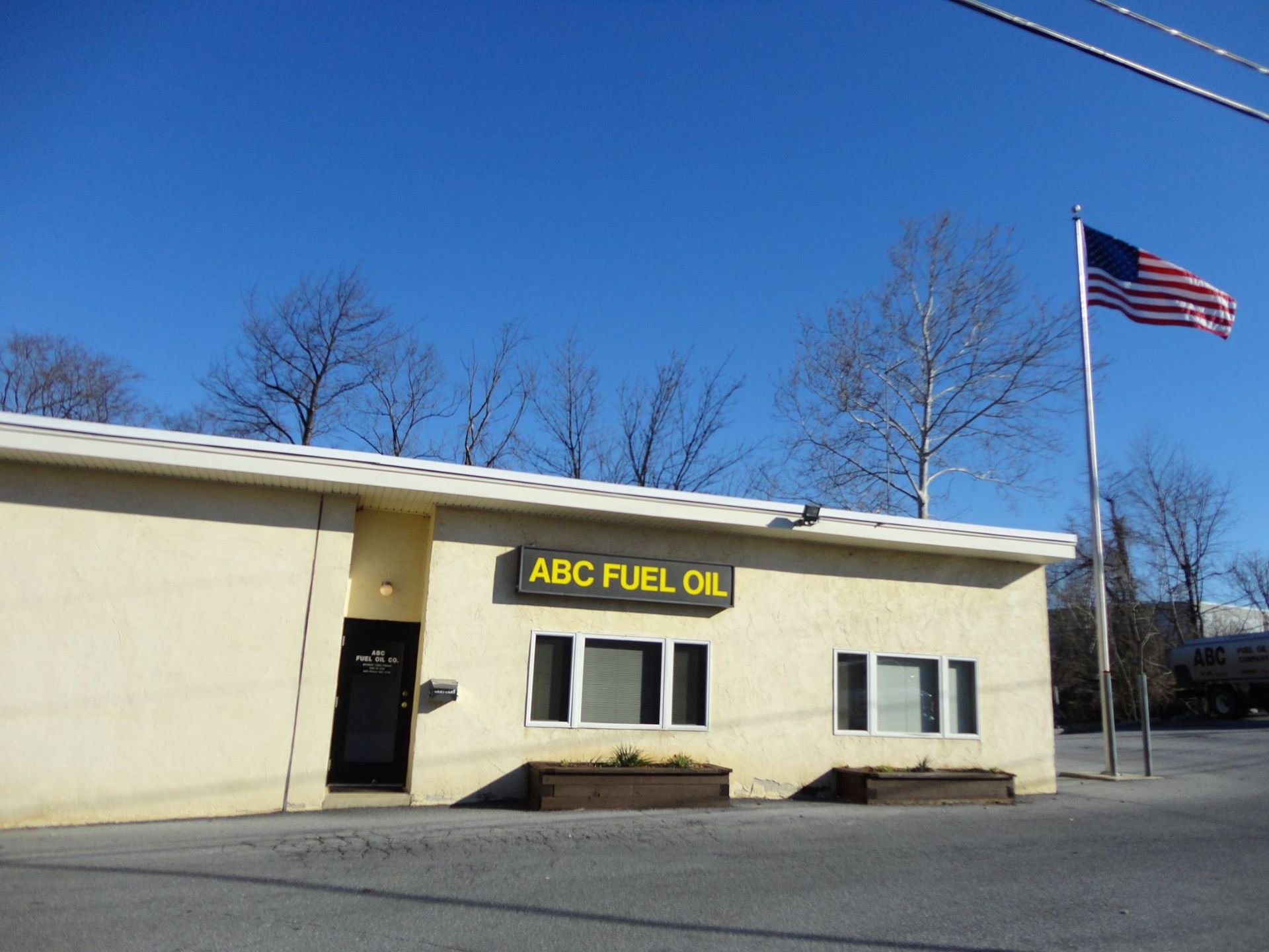 ABC Fuel Oil building with American flag, clear blue sky.