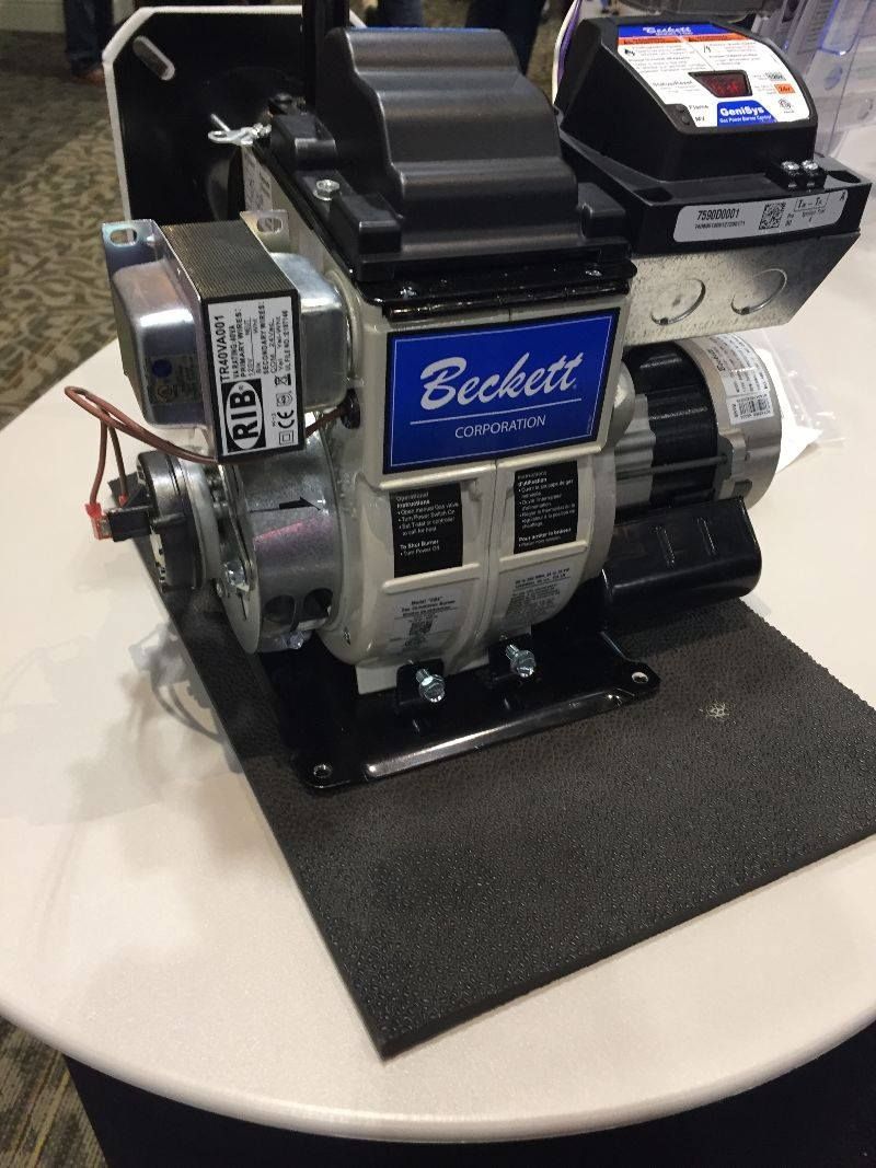 Oil burner machine, Beckett brand, on a white table. Black and silver components, with a black base.