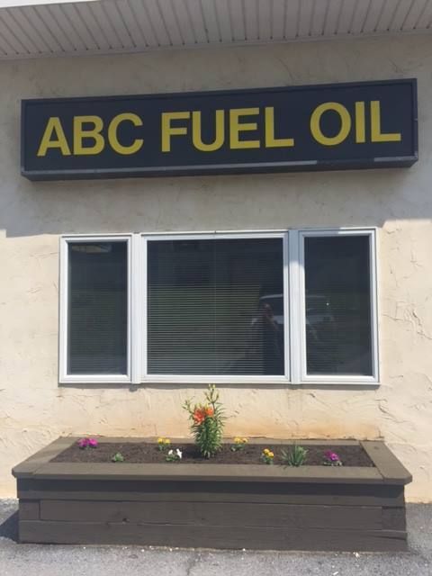 ABC Fuel Oil sign above a window, with a planter box filled with flowers below.