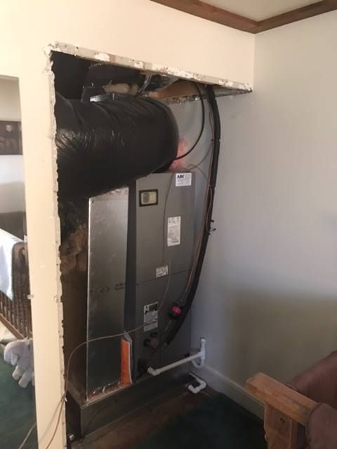 HVAC unit in a wall cavity, with exposed ductwork and plumbing.