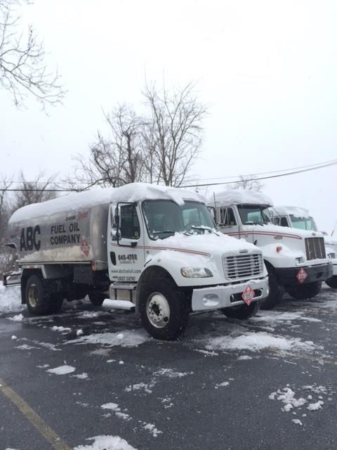 Two fuel oil trucks covered in snow, parked on a snowy lot.