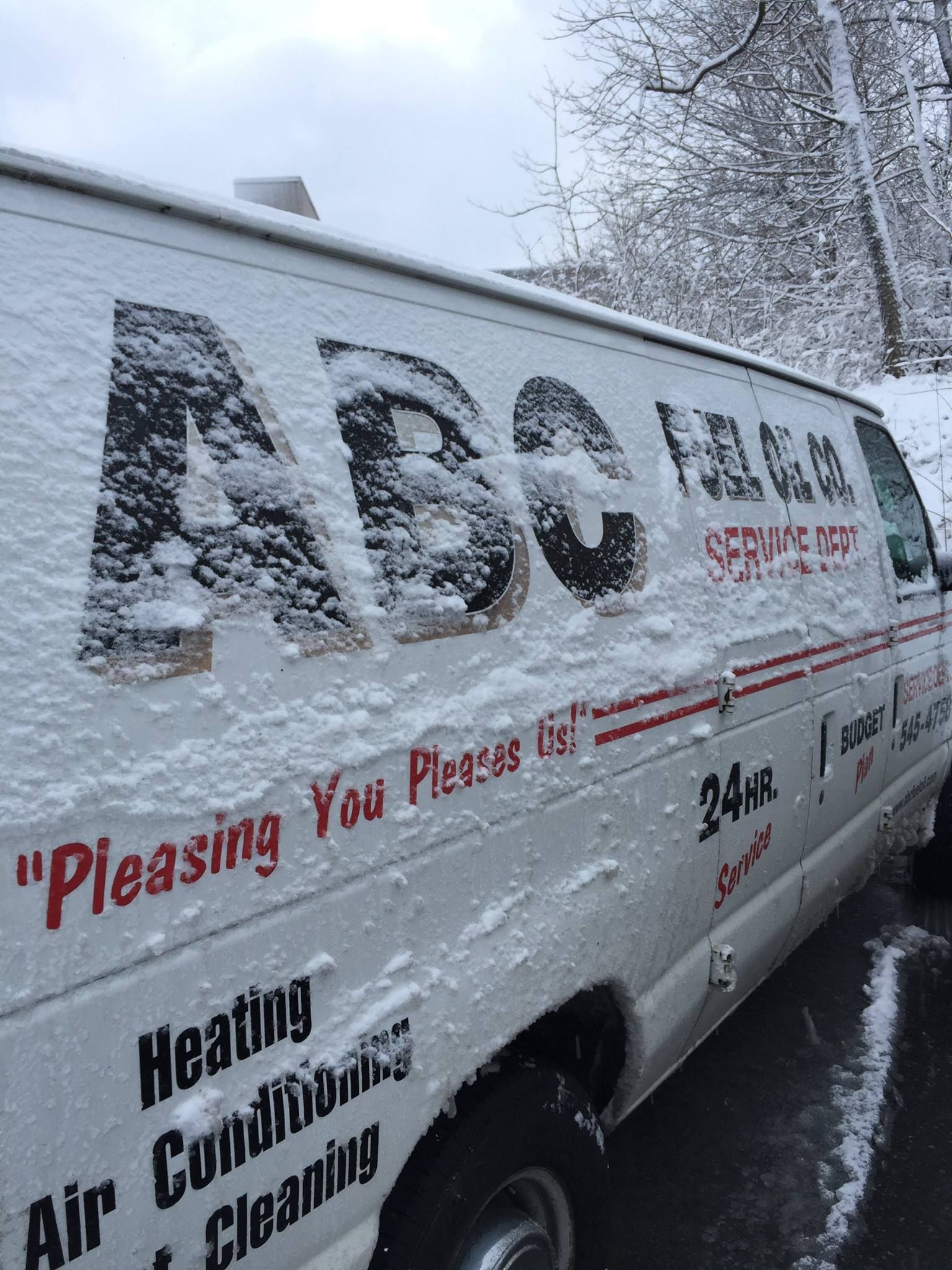 Snow-covered ABC Heating and Air Conditioning van parked on a snowy street.