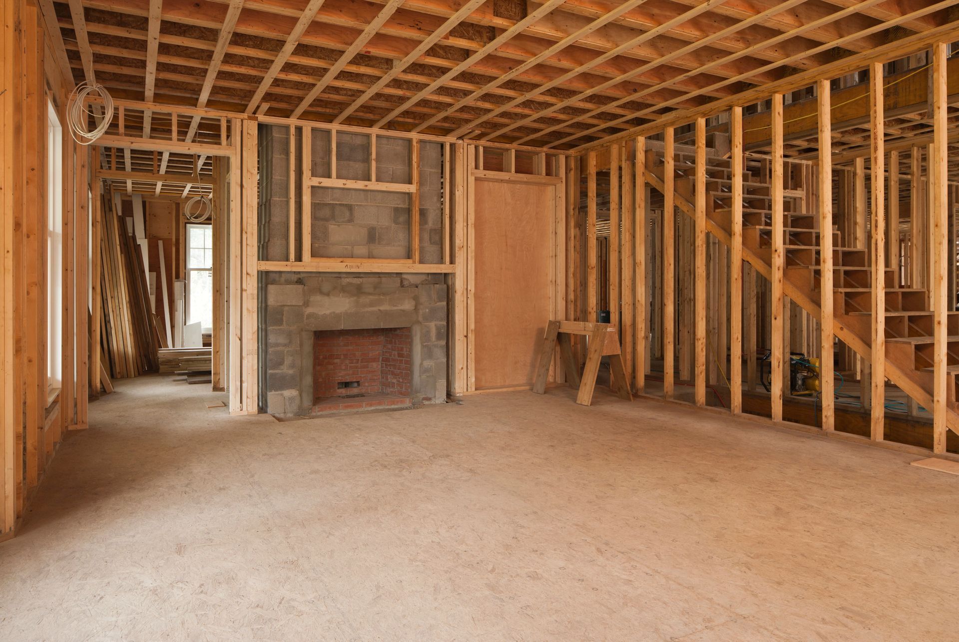 Interior of a house under construction; wooden framework, fireplace, carpeted floor.