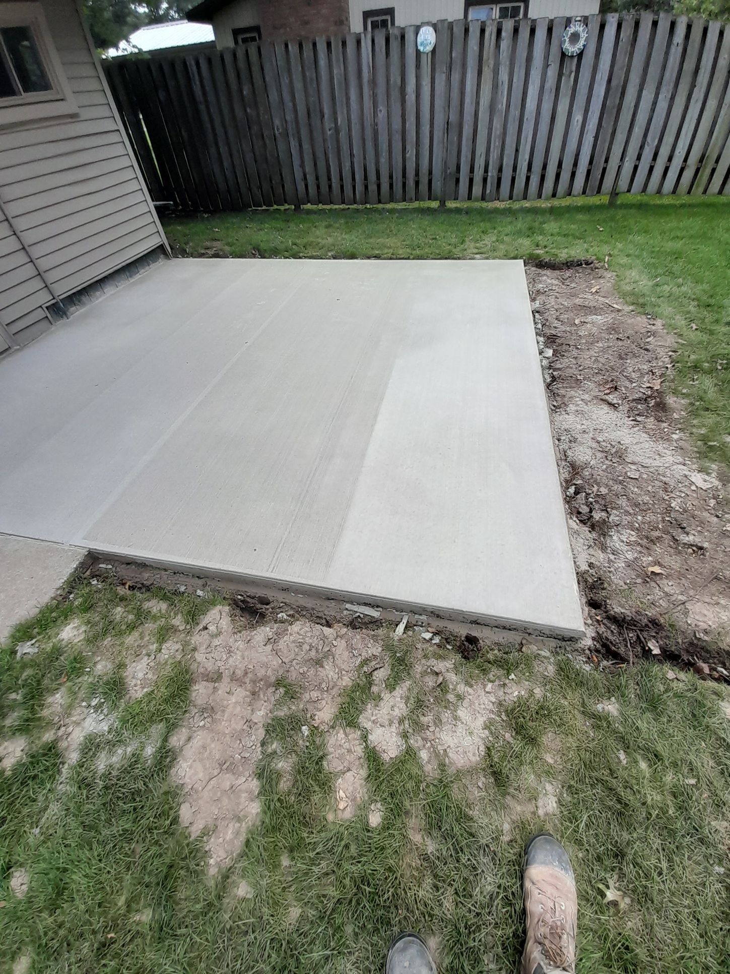 a concrete patio is being built in the backyard of a house 