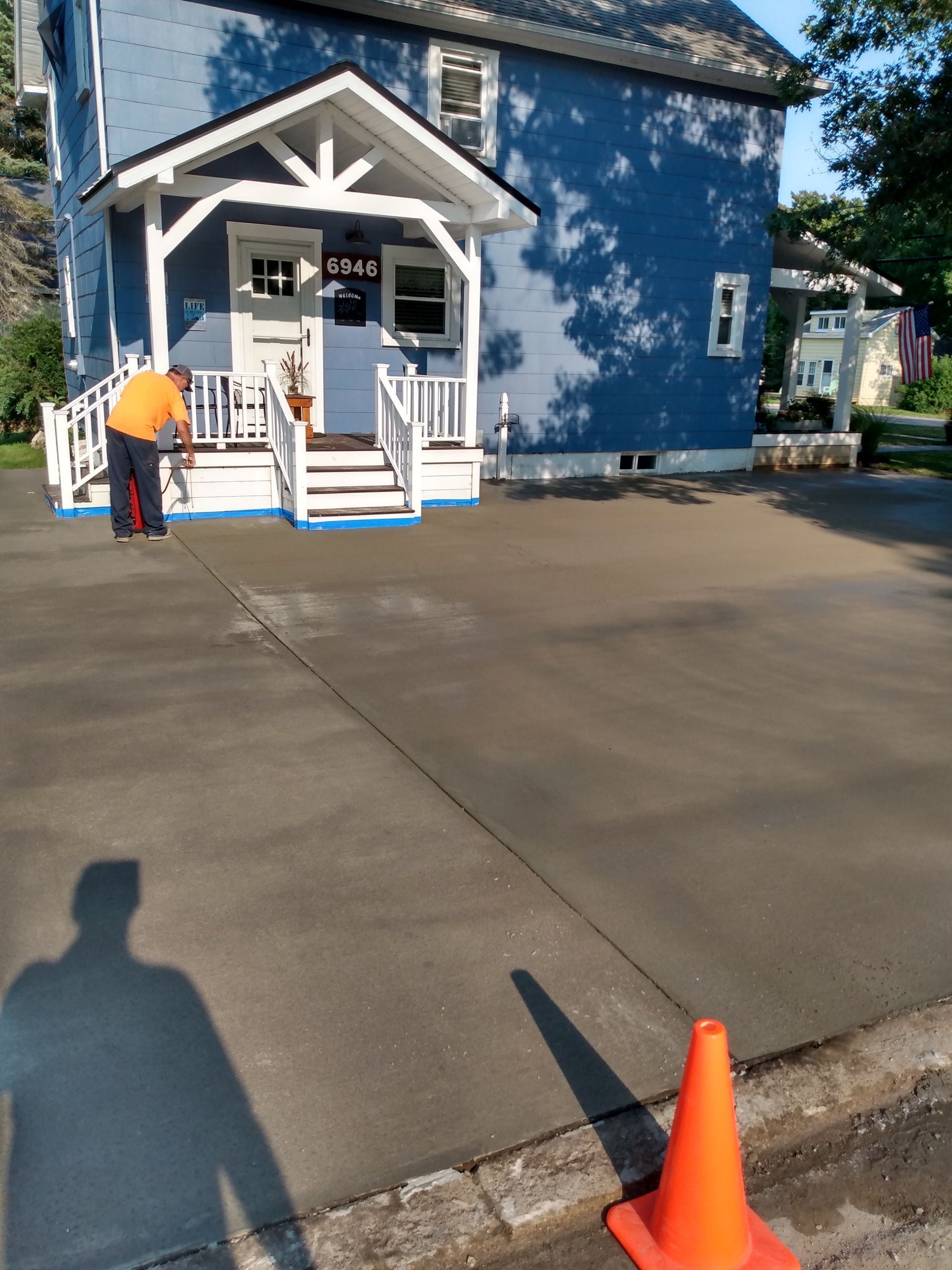 a man is cleaning the driveway in front of a blue house