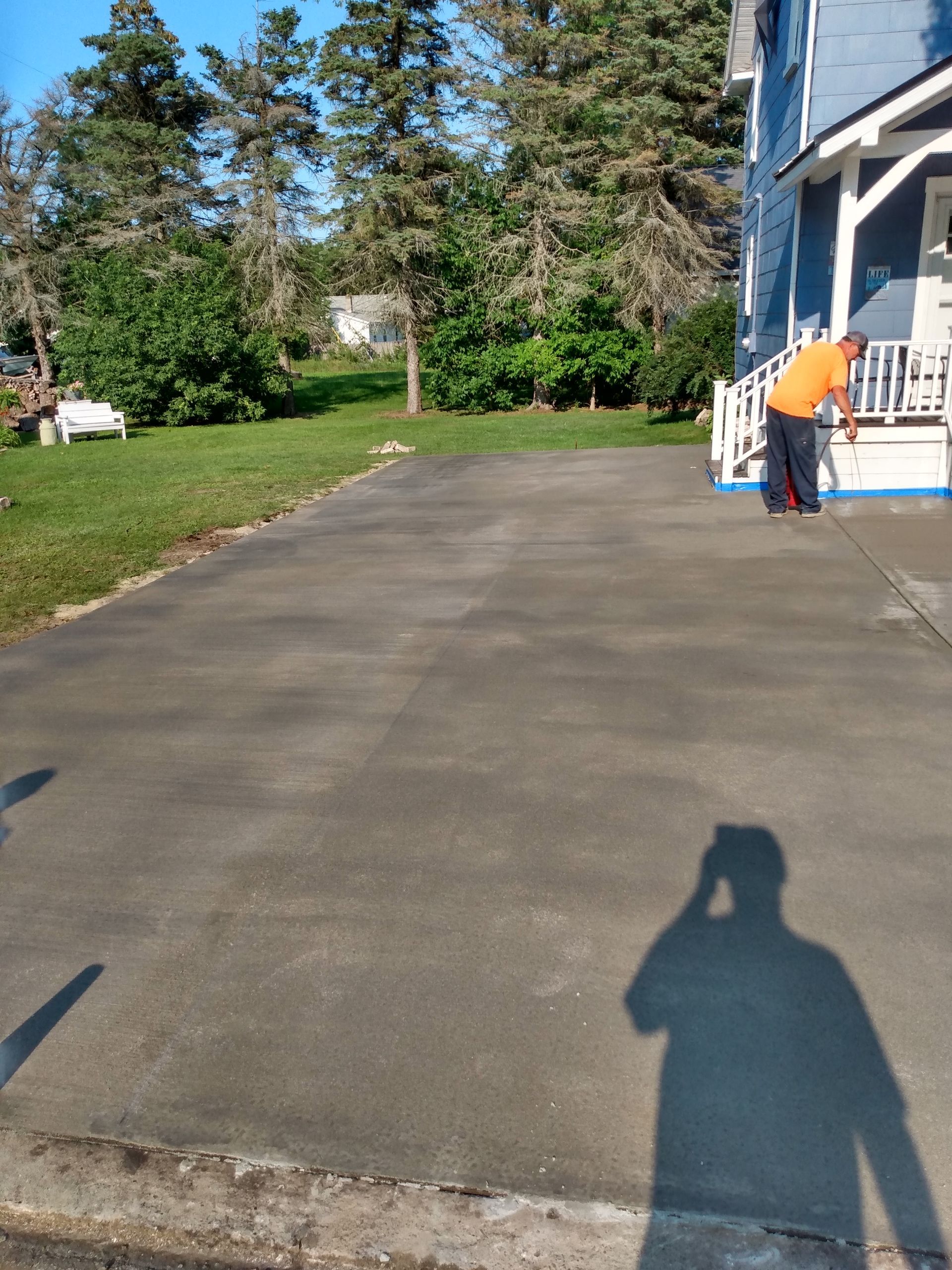 a man is cleaning a driveway in front of a house 