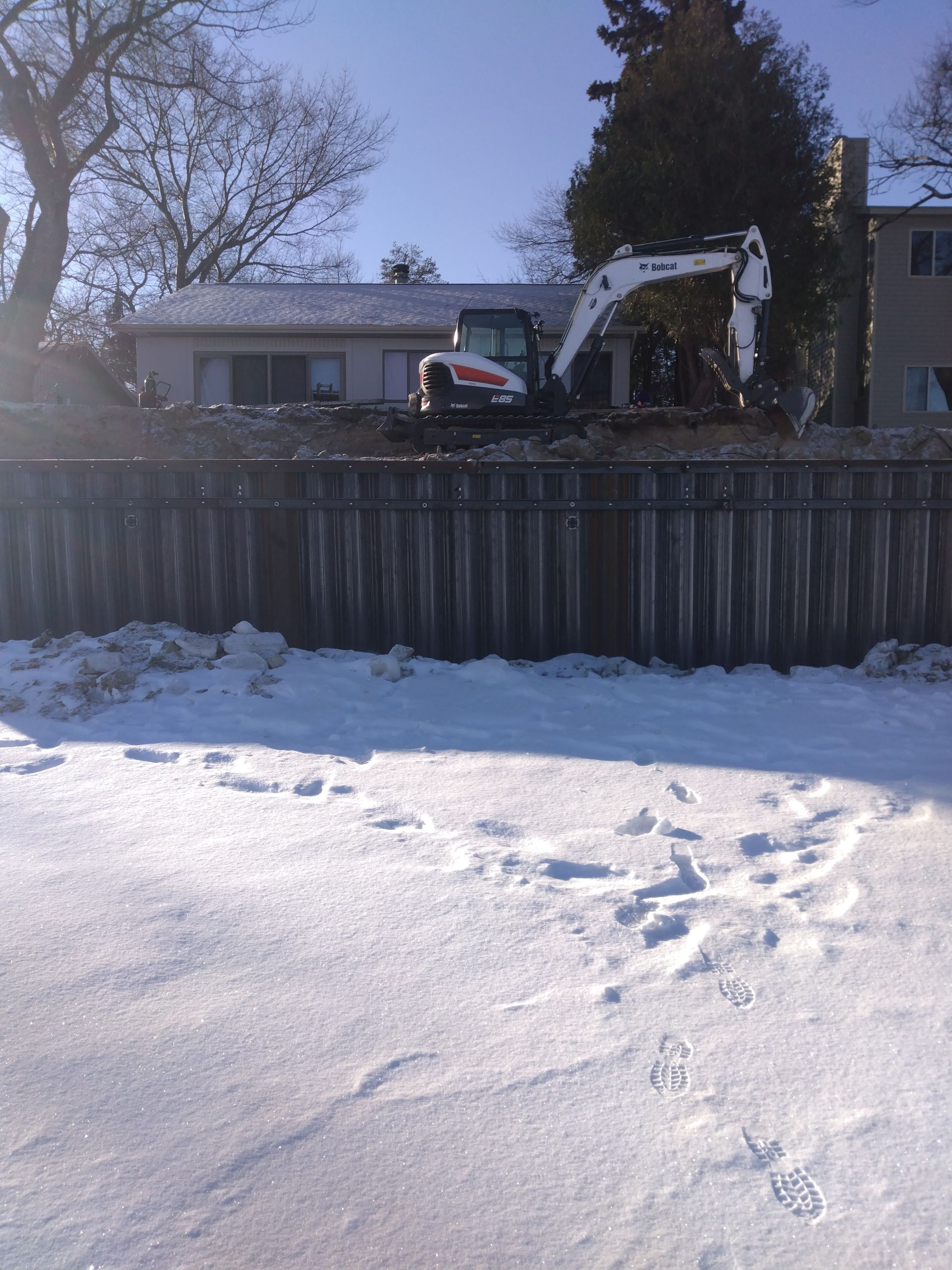 a bobcat excavator is in the snow near a house