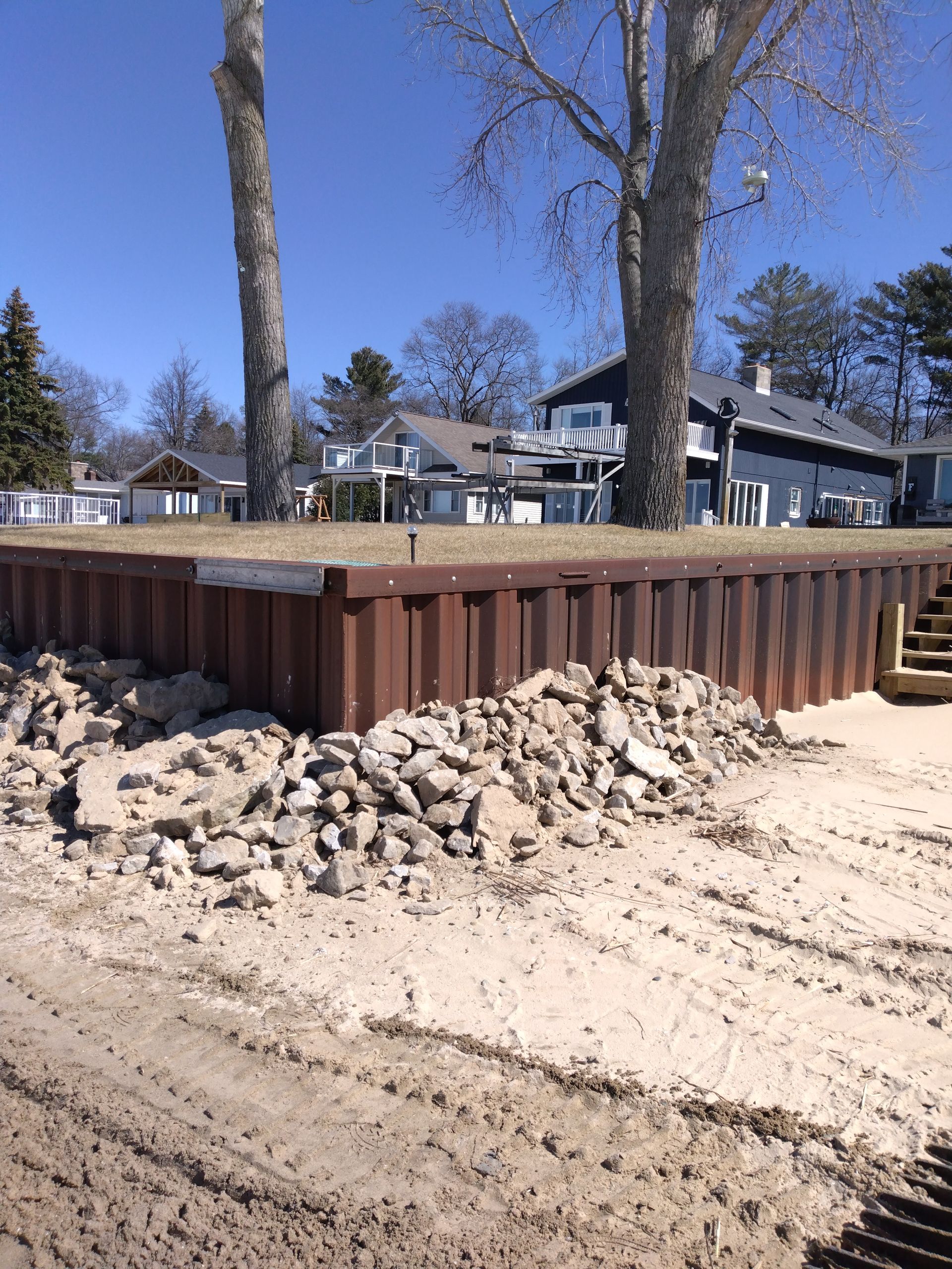 a wooden wall is being built on a dirt road next to a house 