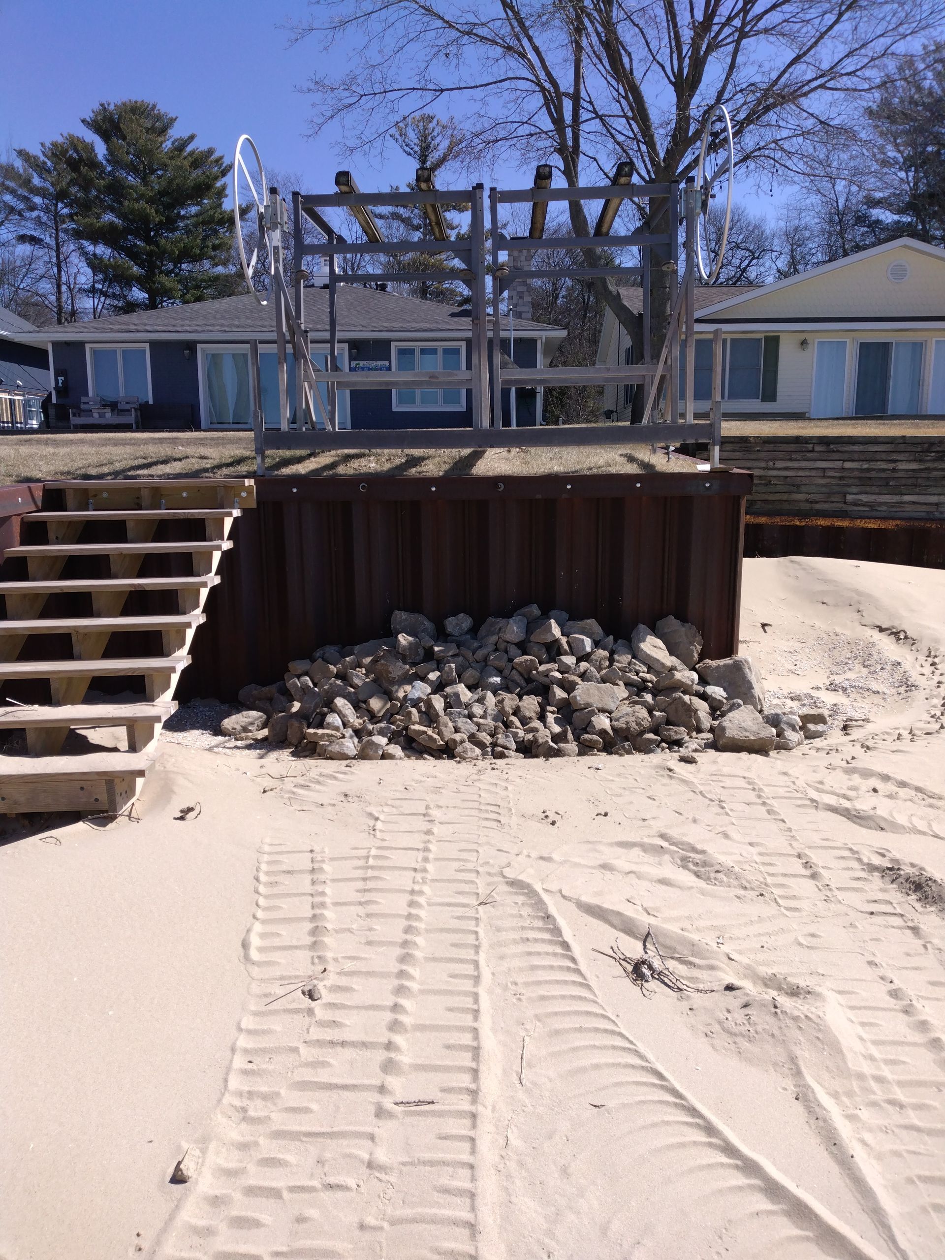 a pile of rocks sits in the sand in front of a house