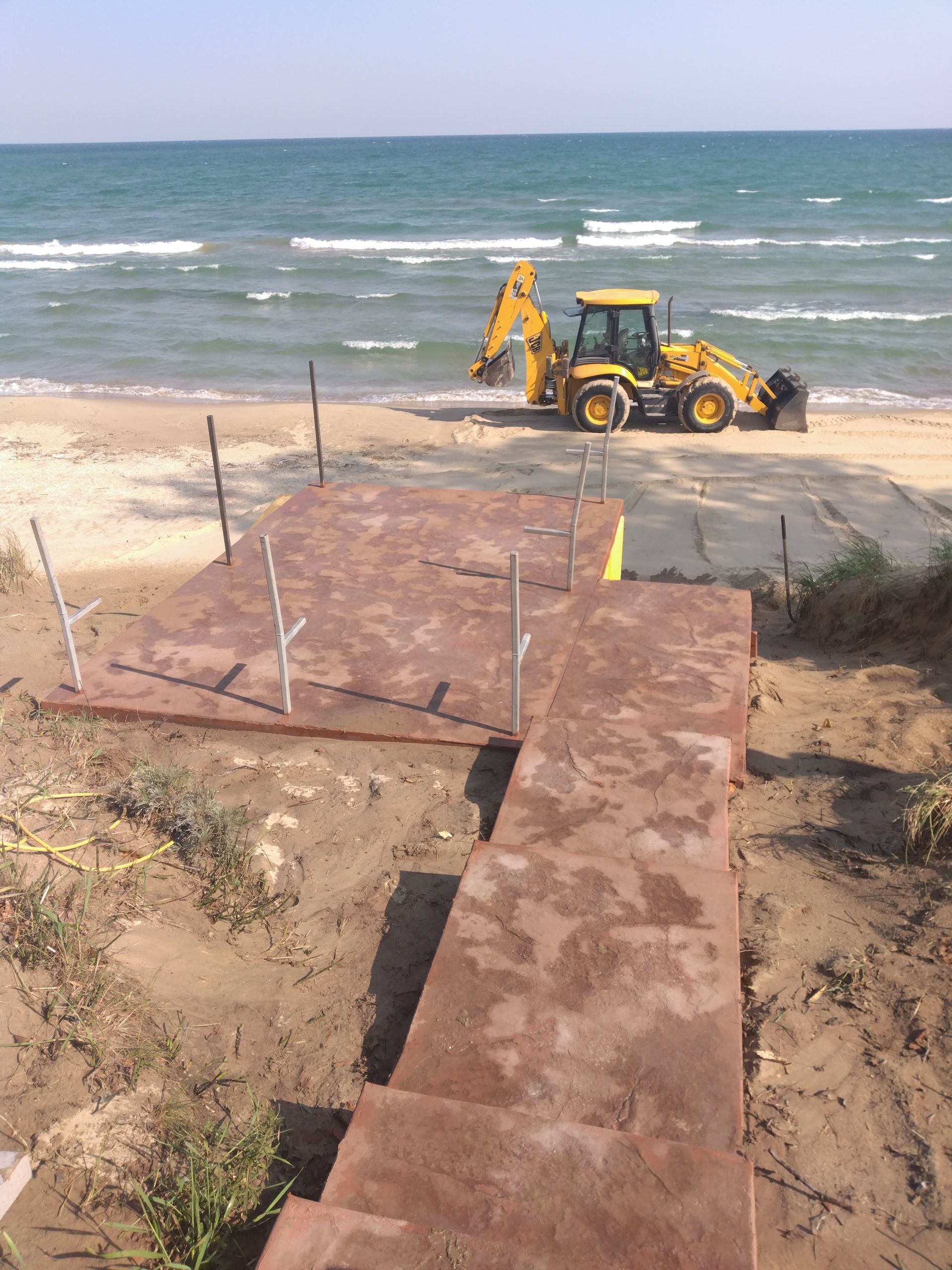 a yellow tractor is parked on the beach next to the ocean 