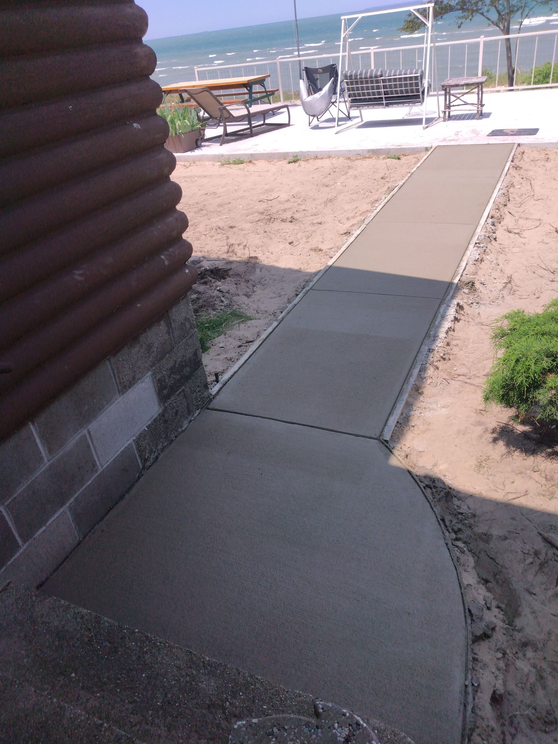 a concrete walkway leading to a picnic area on the beach