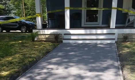 a concrete walkway leading to a house with a car parked in front of it