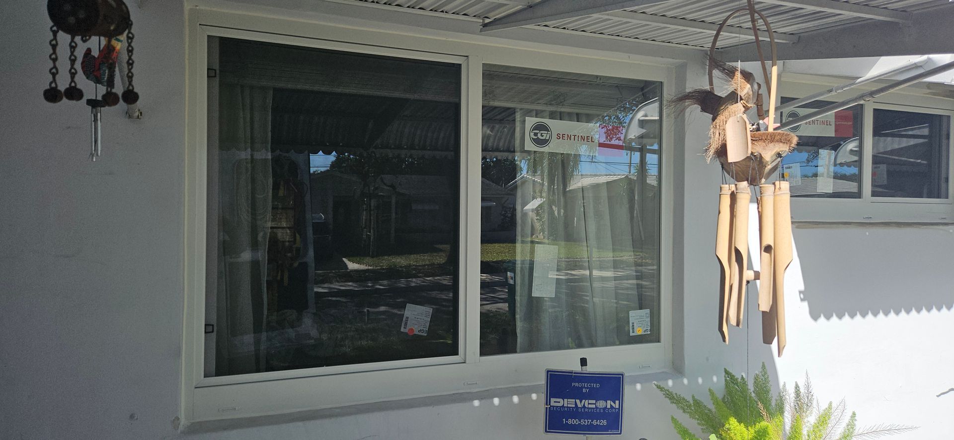 A house exterior with windows, decorated with hanging ornaments and a security sign below.