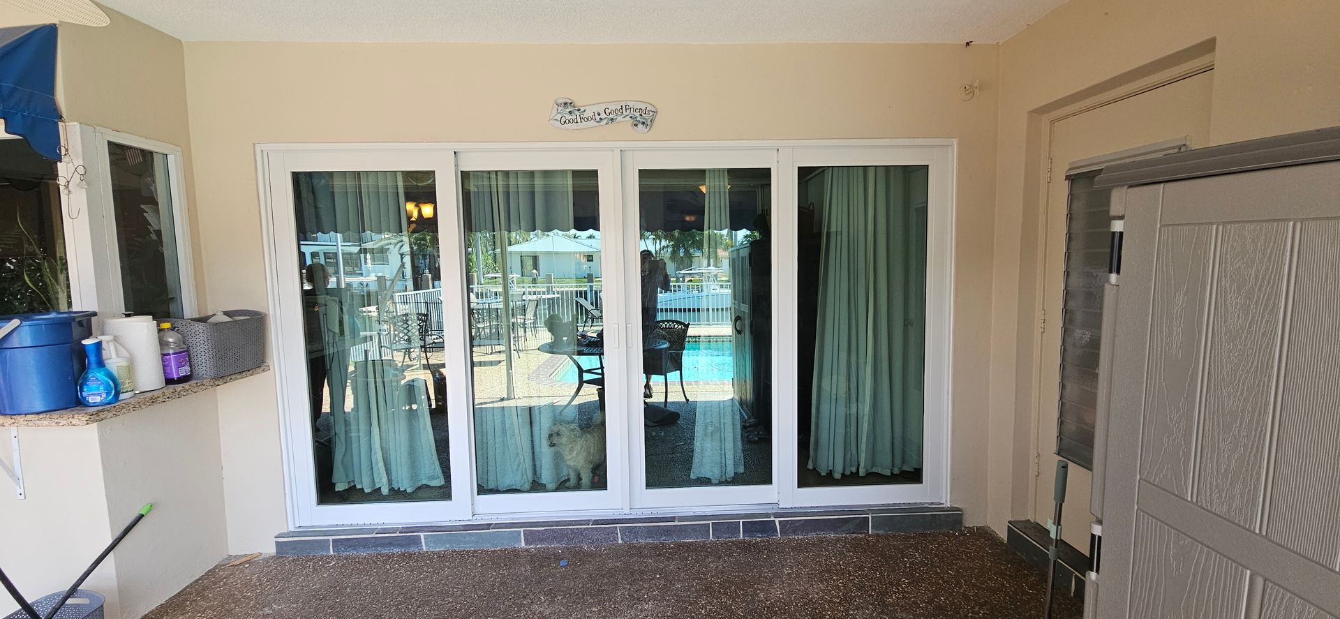 Exterior view of a sliding glass door and window next to a counter with cleaning supplies.