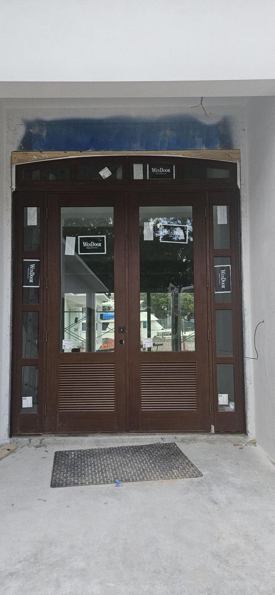 Brown double doors with glass panels and a welcome mat.