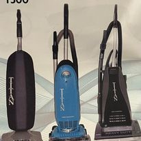 Three vacuum cleaners are sitting next to each other on a table
