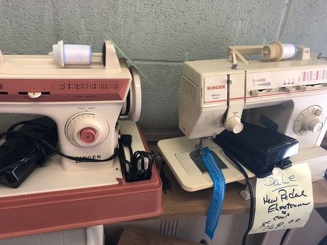A singer sewing machine is sitting on a table next to another sewing machine