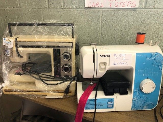 Two sewing machines are sitting on a wooden table