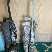 Two vacuum cleaners are sitting next to each other on a rug