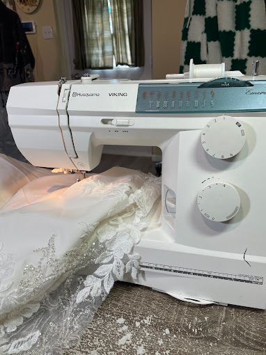 A white sewing machine is sitting on a table next to a piece of lace