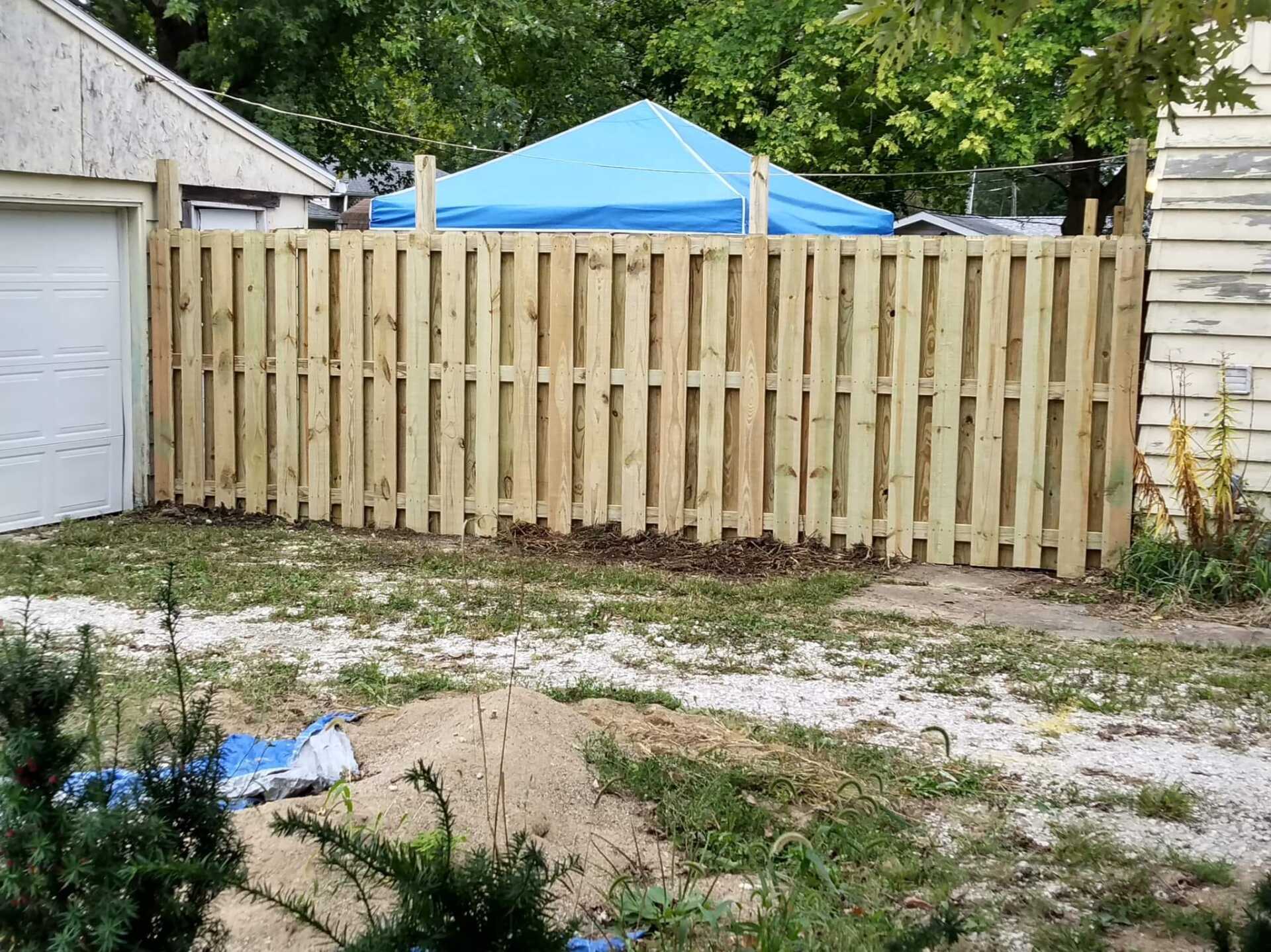 tall wooden fence next to a white garage door