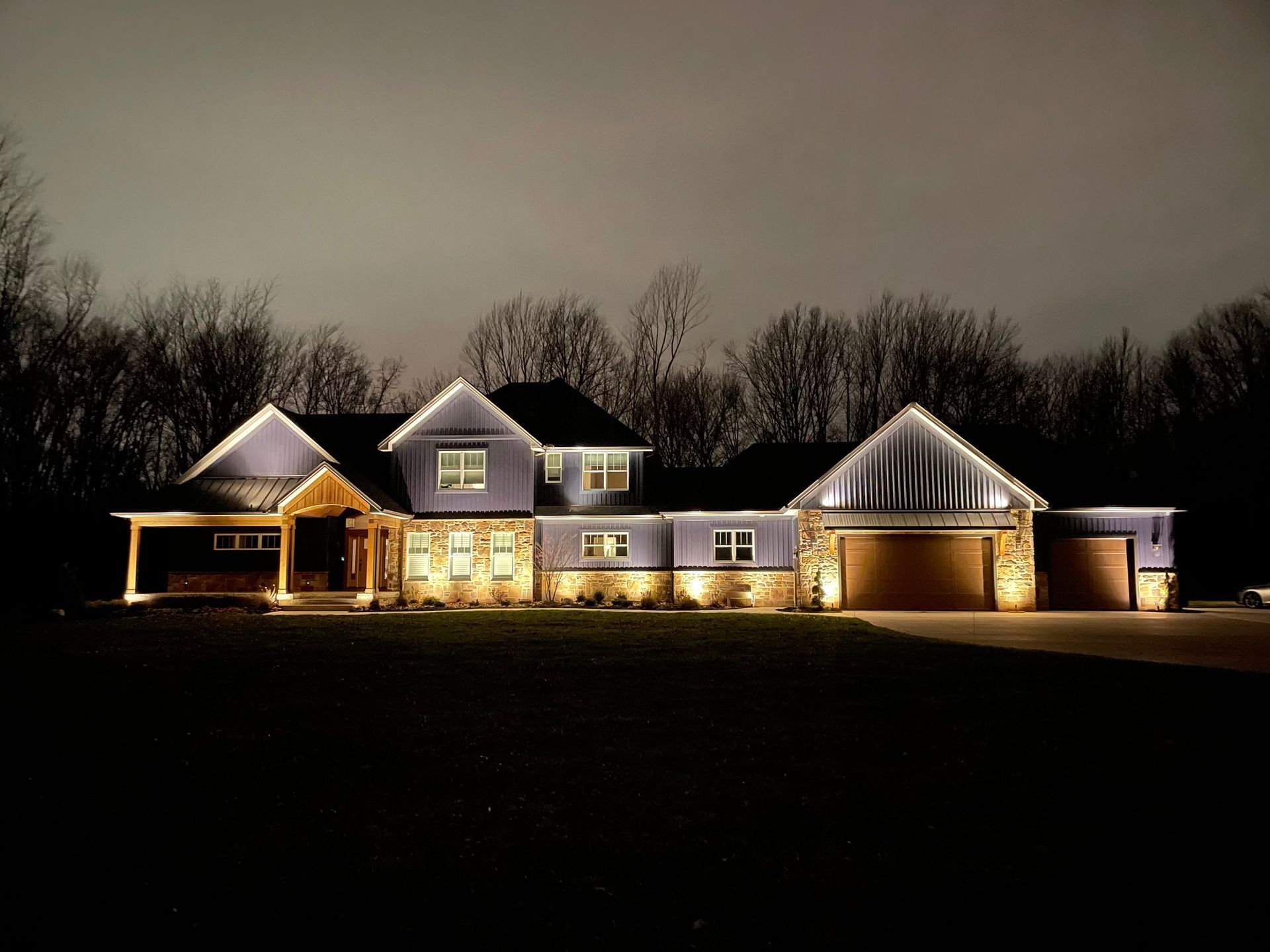 Illuminated multi-section house at night with a cloudy sky.