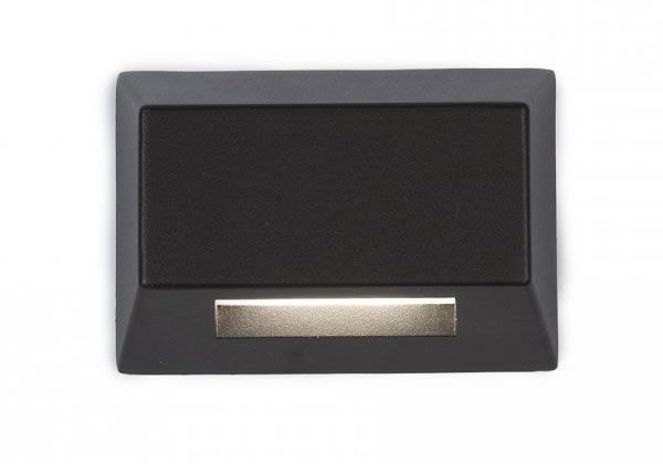 Black rectangular outdoor step light with a recessed light emitting a warm glow.