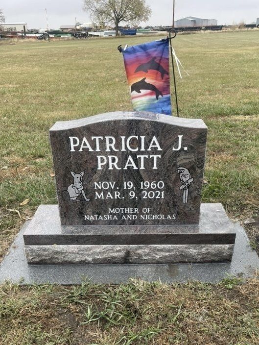 A gravestone for patricia j. pratt in a cemetery with a flag in the background.