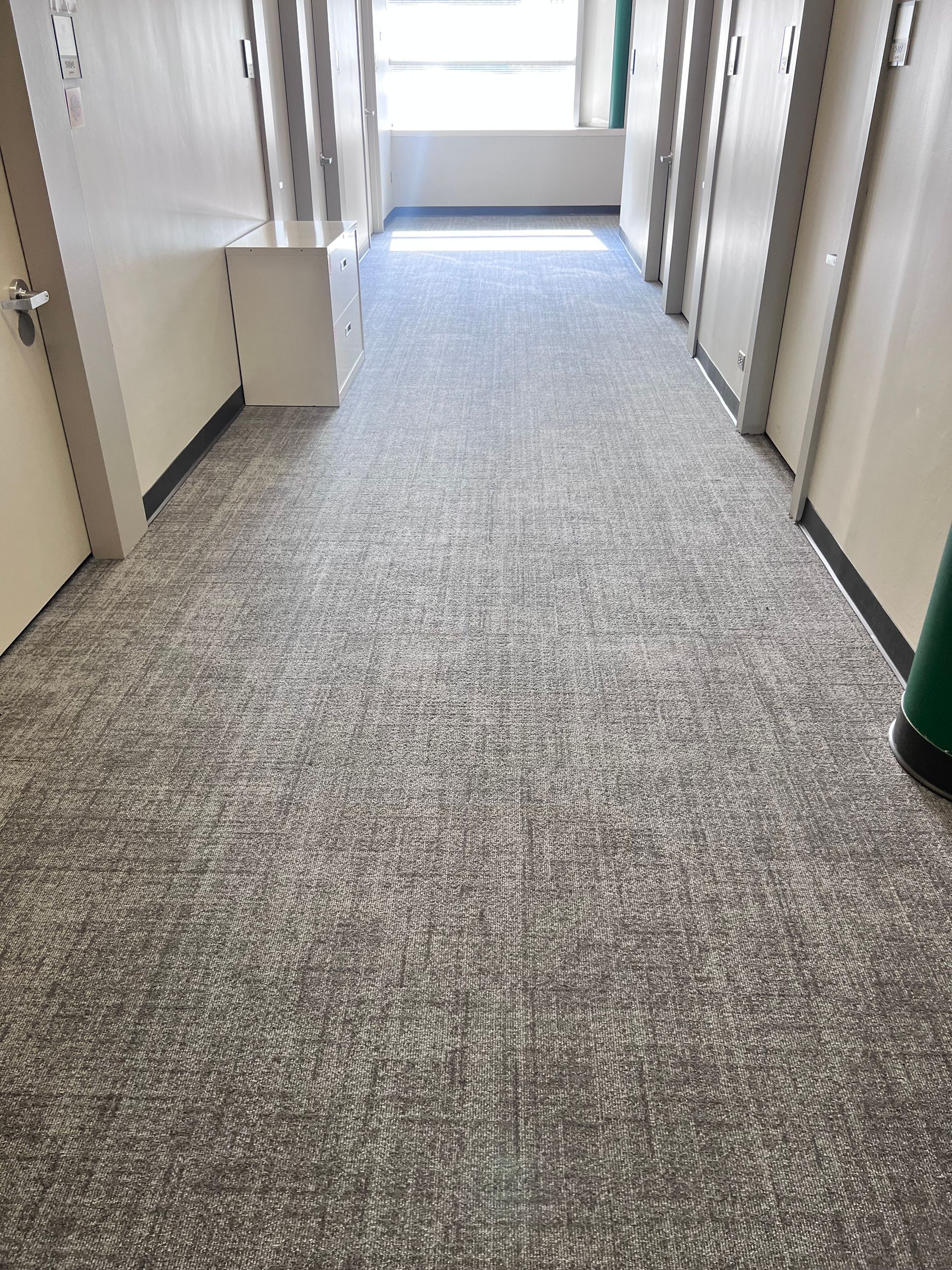 A long hallway with a gray carpet and white walls