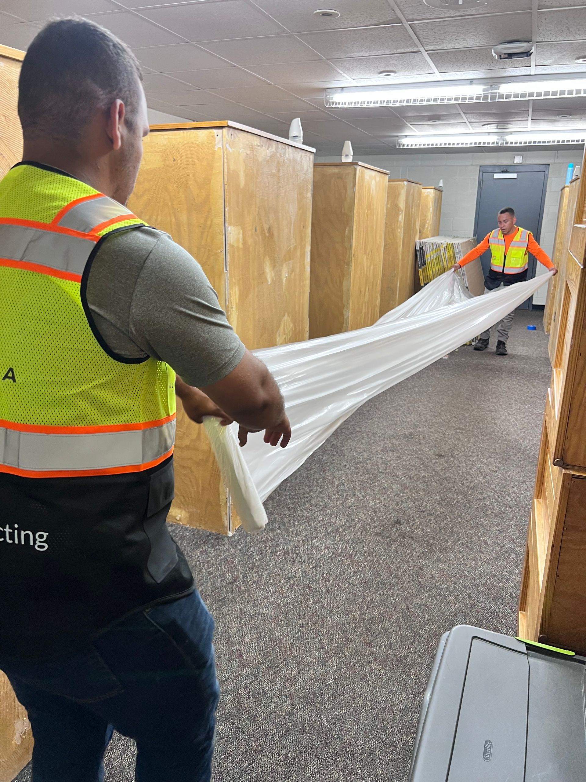 A man in a yellow vest is holding a piece of paper in a room.