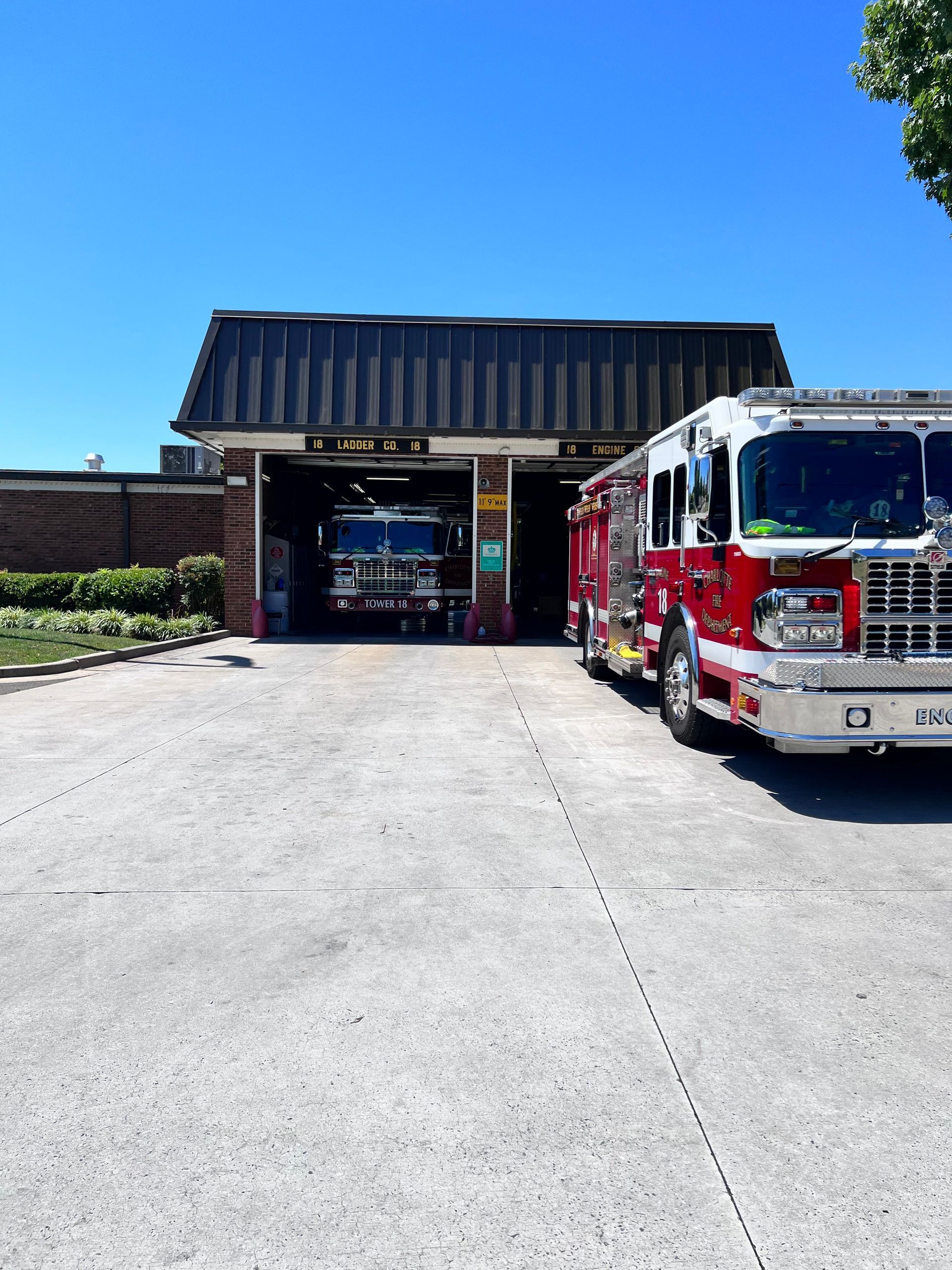 Two fire trucks are parked in front of a fire station