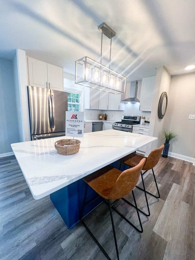 A kitchen with a table and chairs and a stainless steel refrigerator.