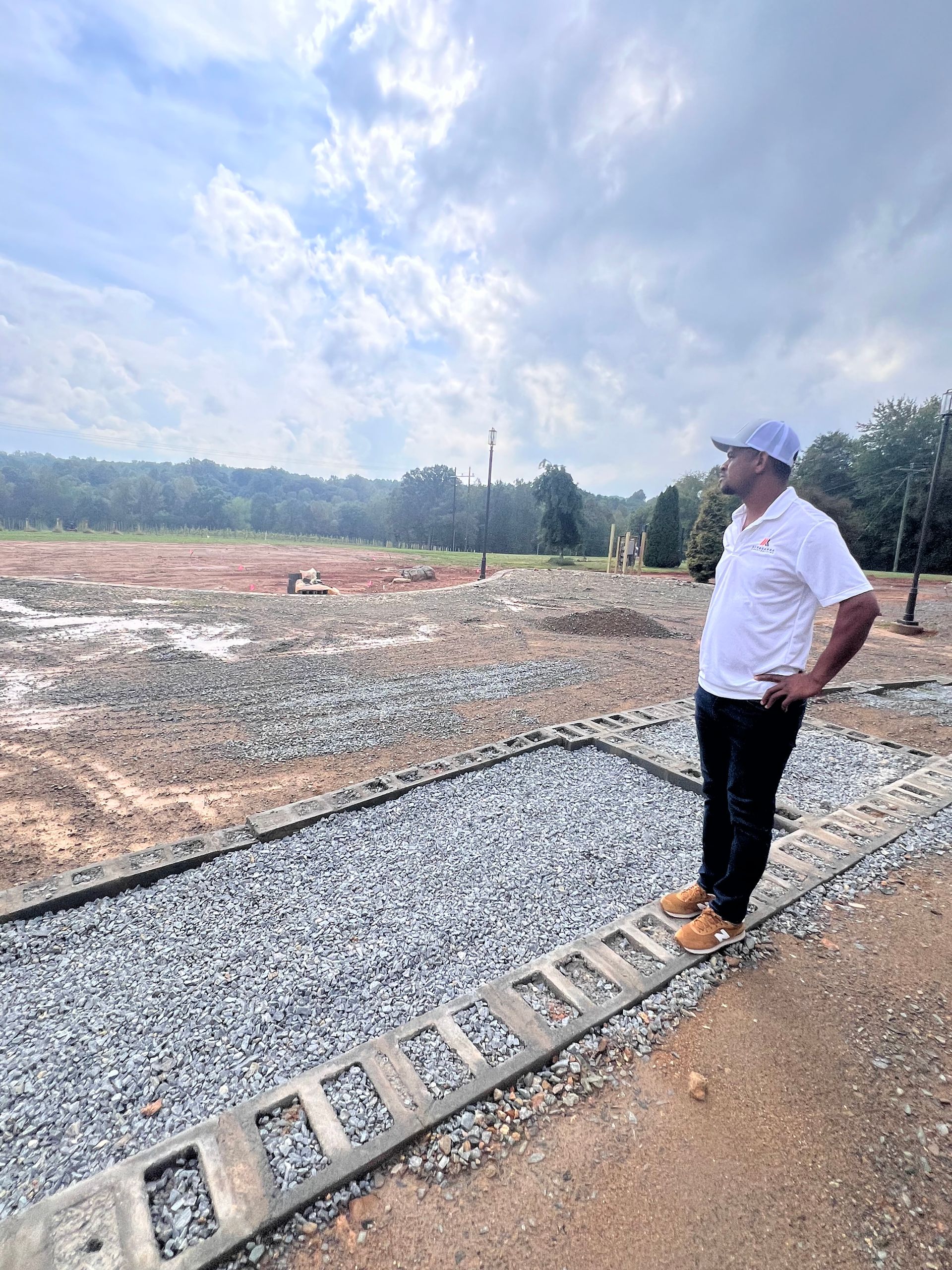 A man is standing next to a ladder on a gravel road.
