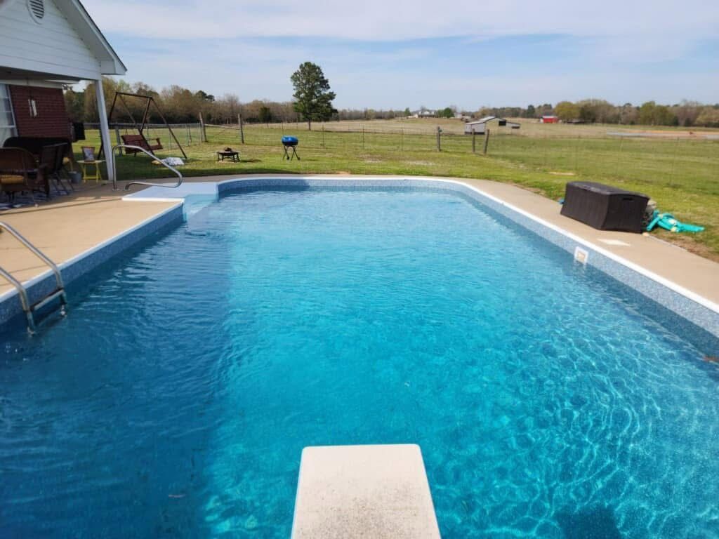 A large swimming pool with a diving board in the middle of it.