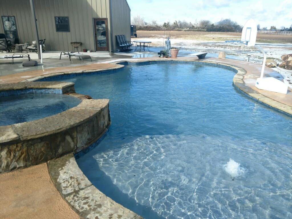 A large swimming pool with a hot tub in the middle of it.