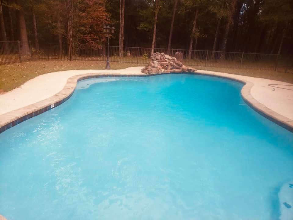 A large swimming pool surrounded by trees in a backyard.