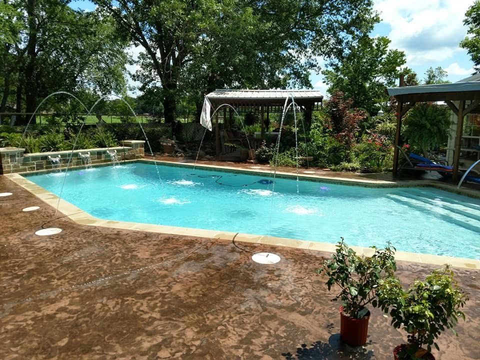 A large swimming pool surrounded by trees and plants