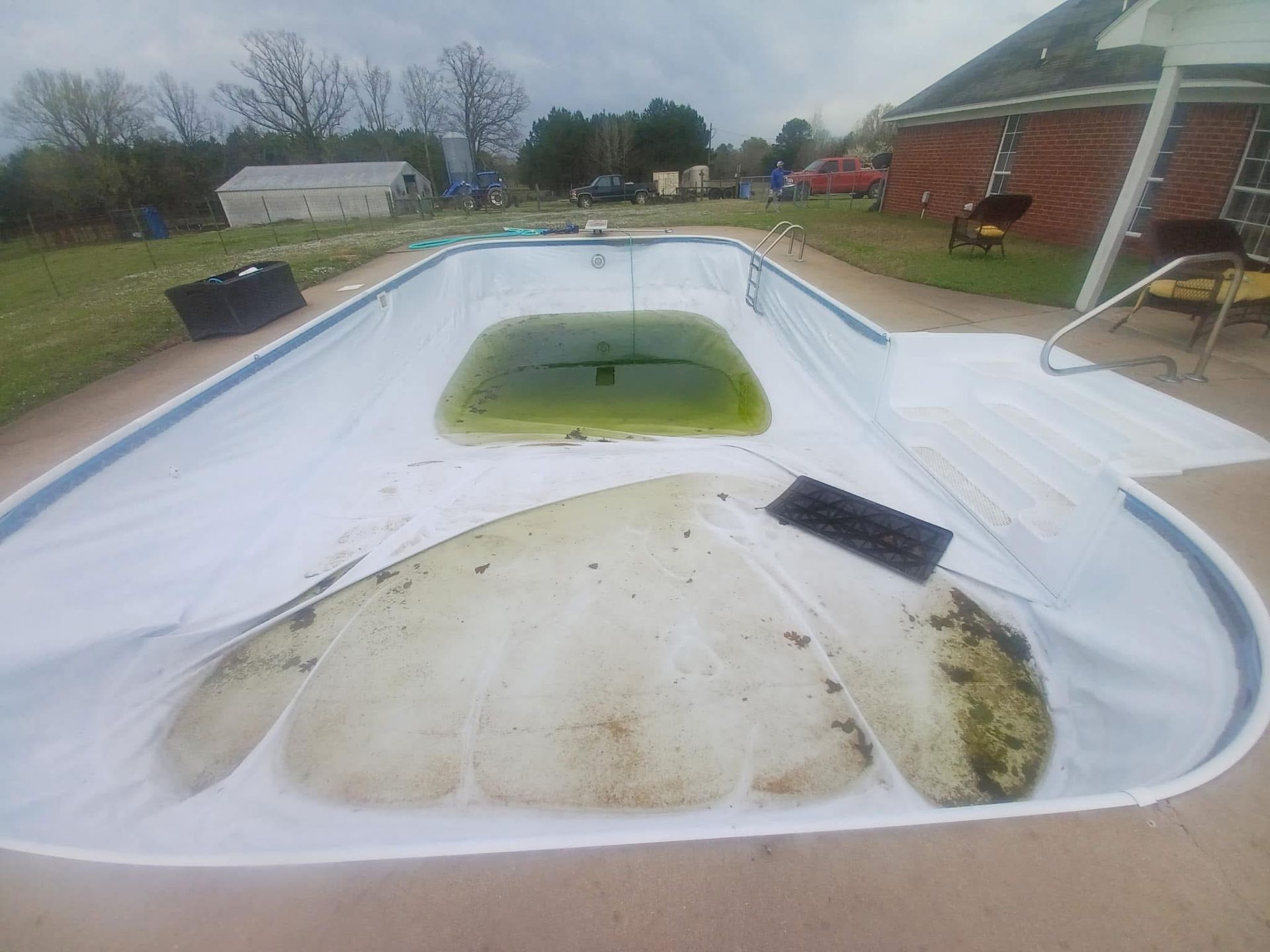 A swimming pool with a white cover on it is being remodeled.