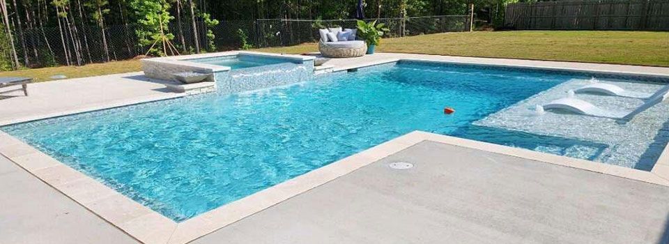 A large swimming pool surrounded by lawn chairs and a fence in a backyard.