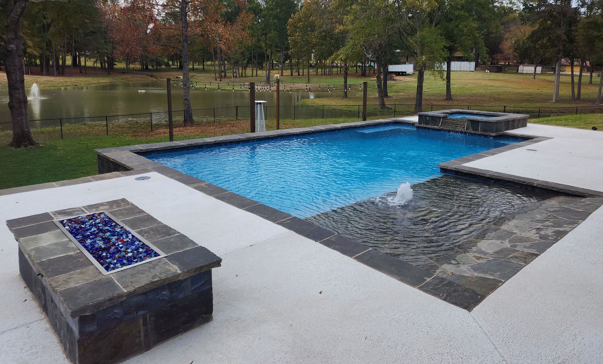 A large swimming pool with a fire pit next to it.