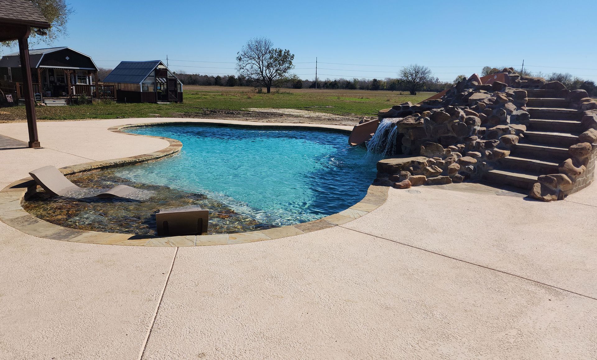 A large swimming pool with a waterfall in the middle.