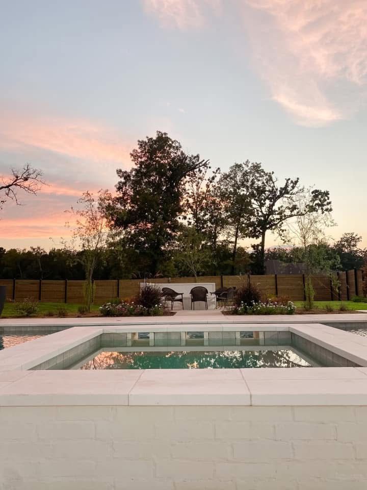 A large swimming pool with a sunset in the background.