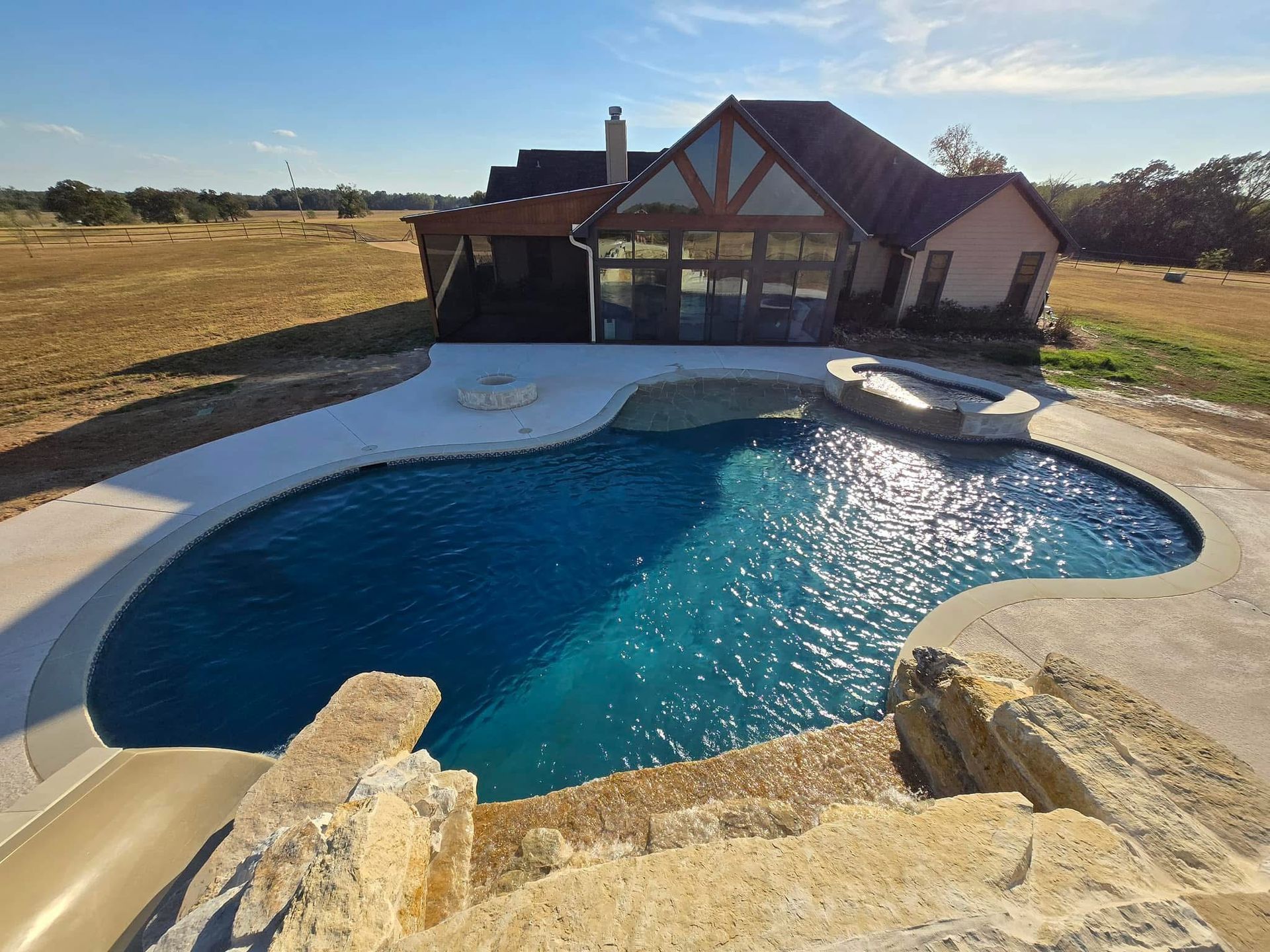 A large swimming pool with a house in the background.