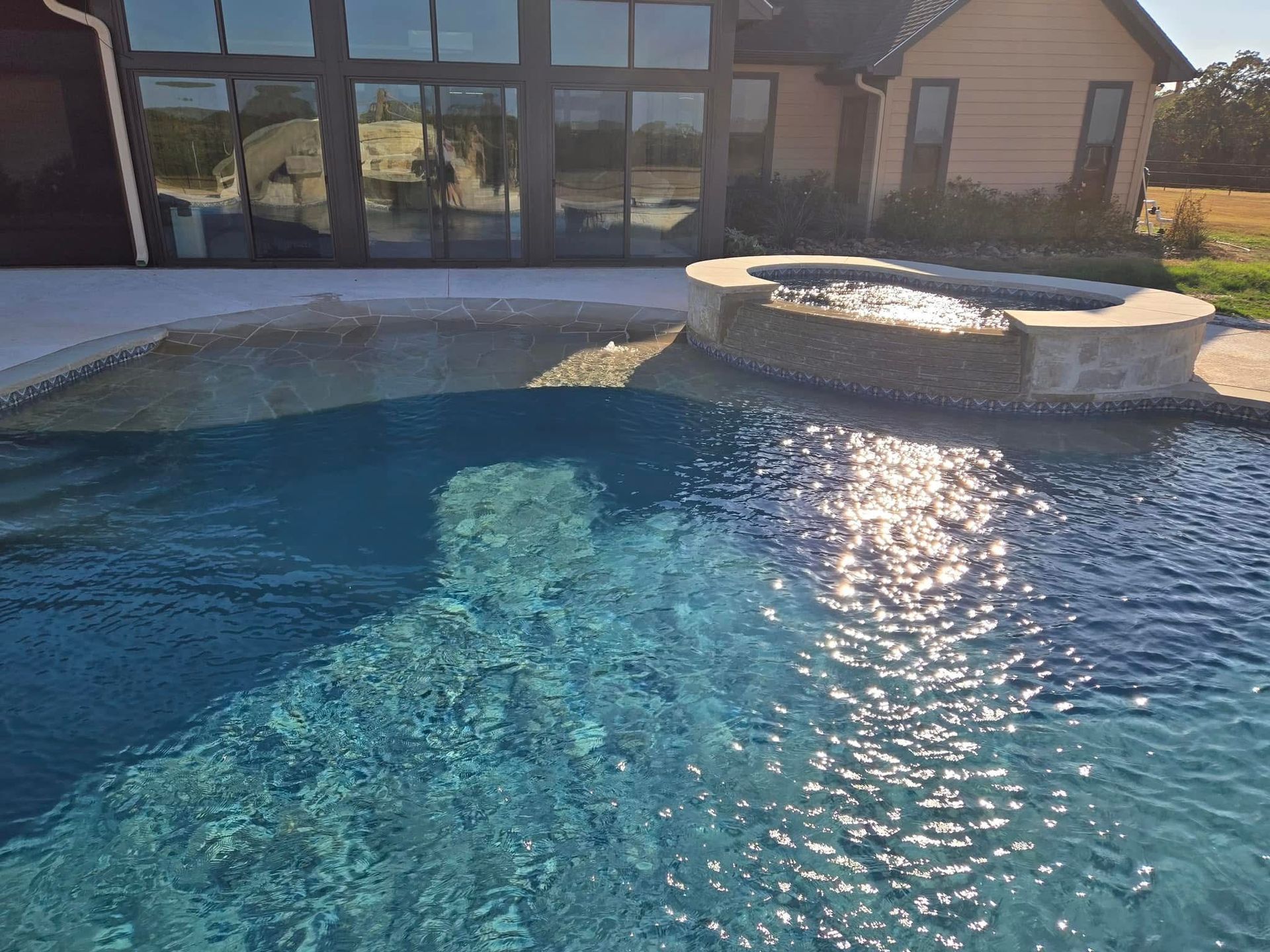 A large swimming pool with a house in the background.