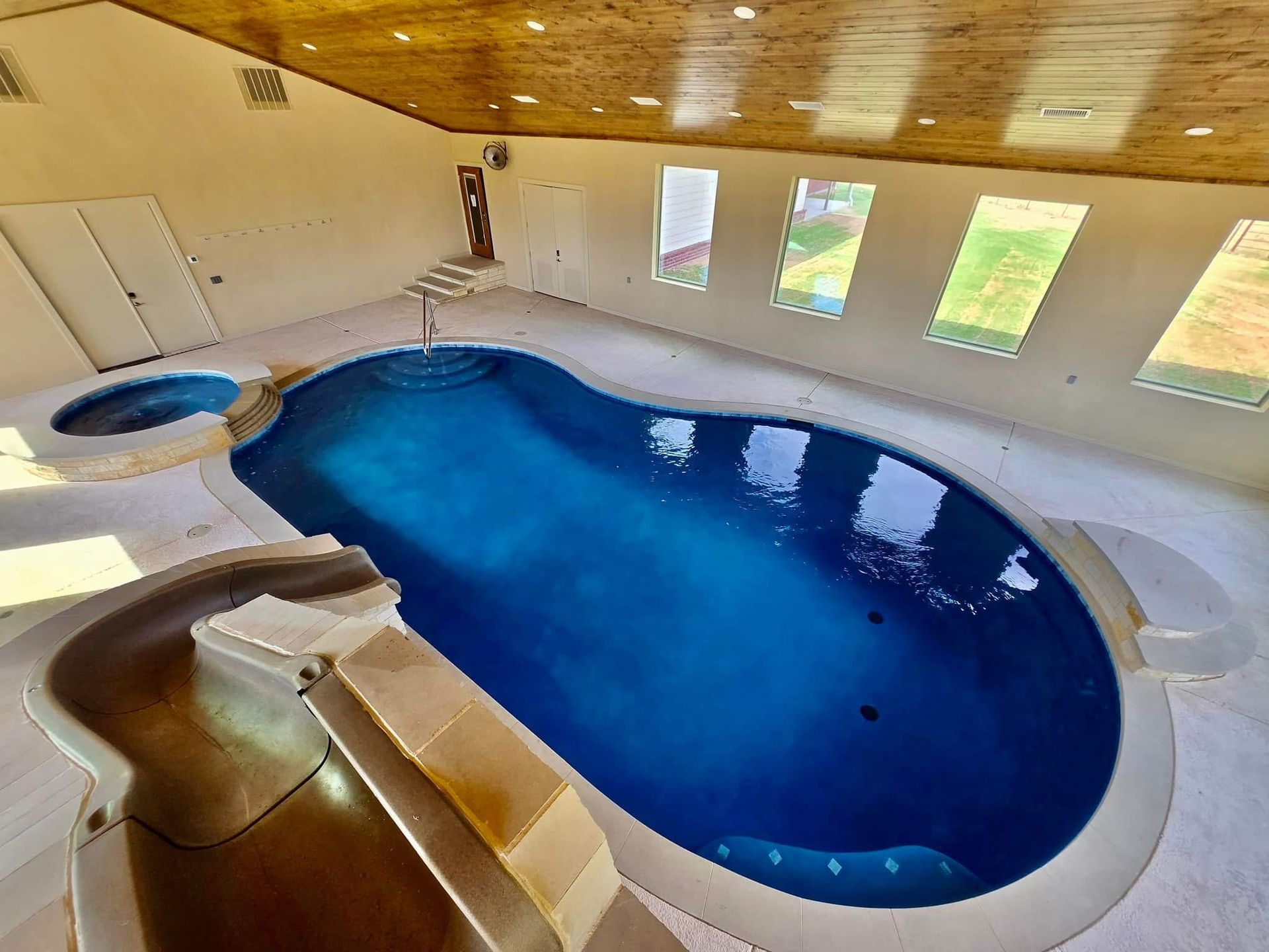 A large indoor swimming pool with a slide and stairs.