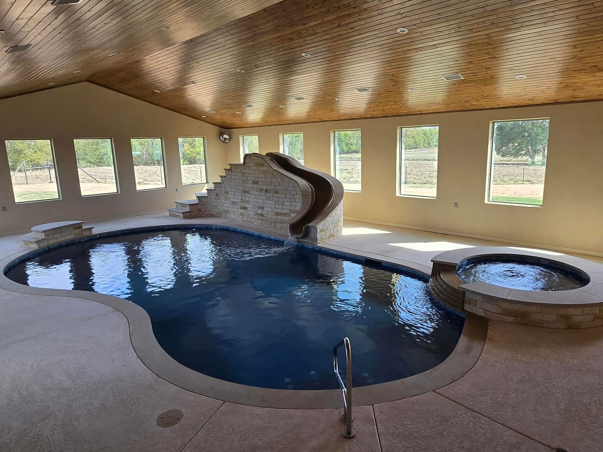 A large indoor swimming pool with a slide and stairs.