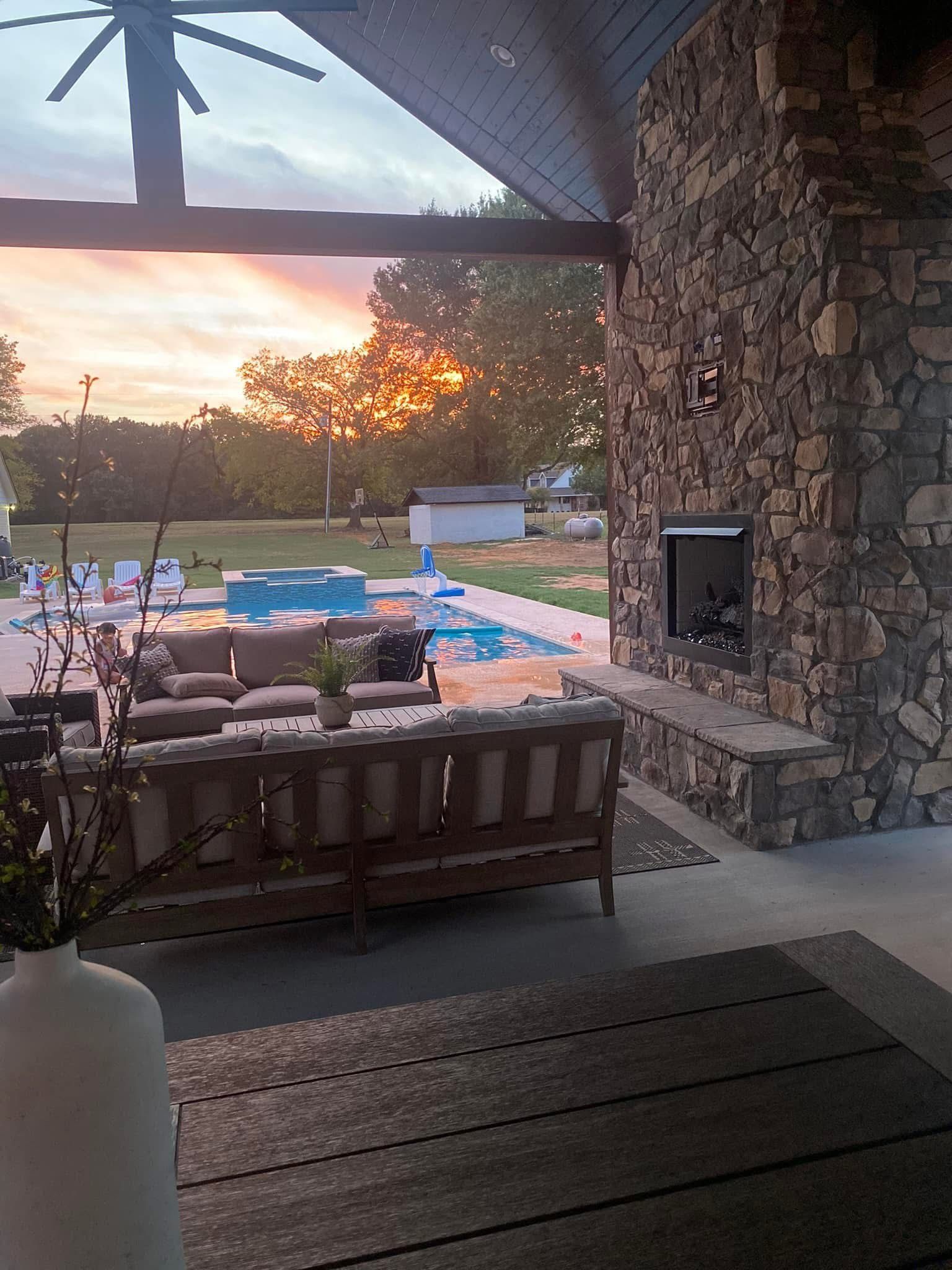 A living room with a fireplace, couch, and a pool.