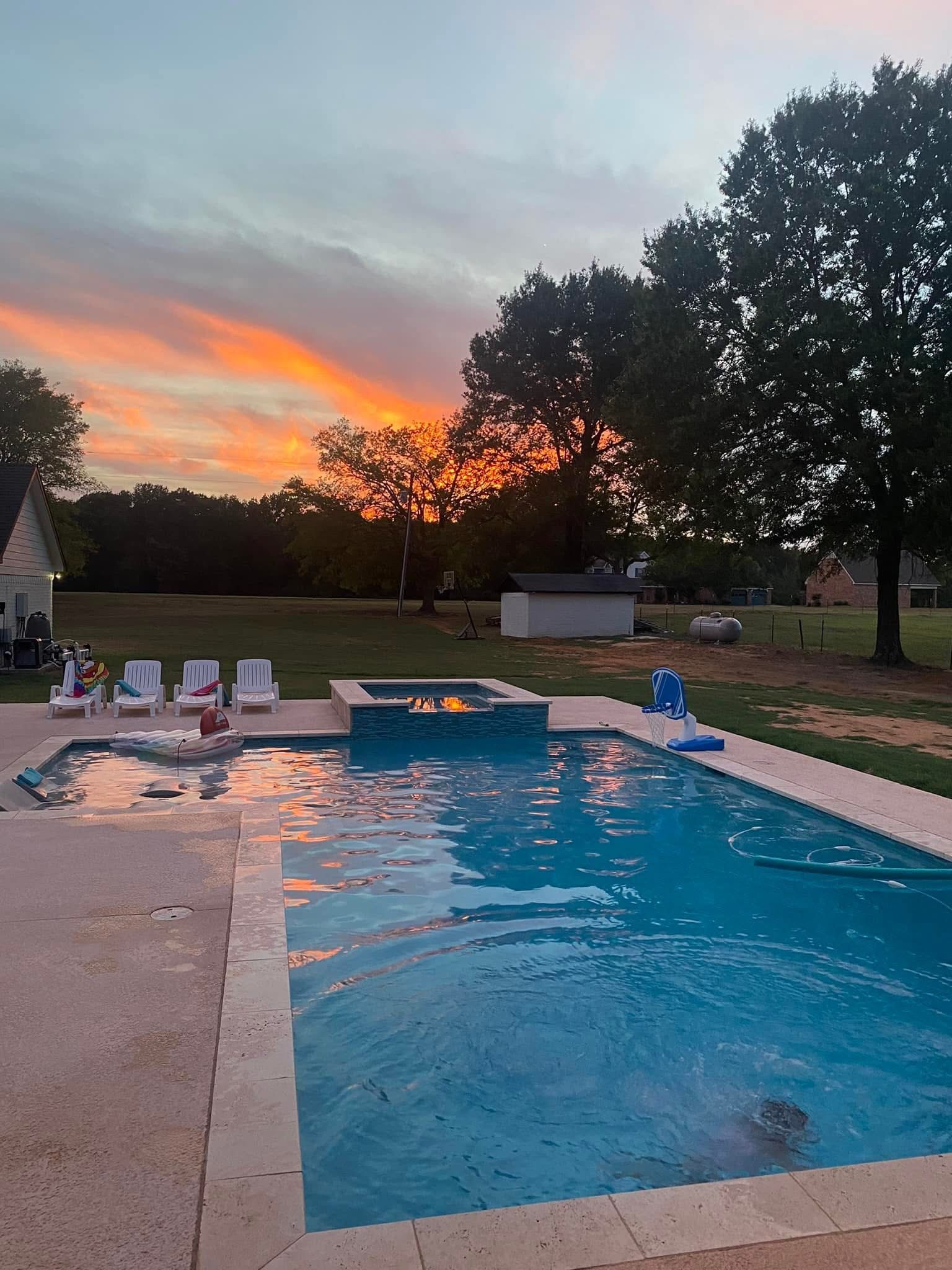 A large swimming pool with a sunset in the background.